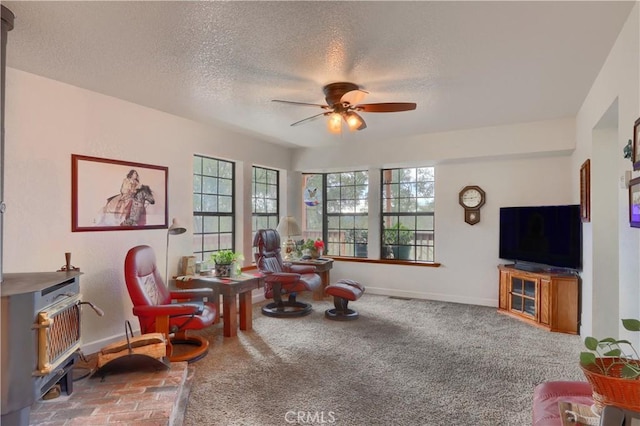 living area featuring a textured ceiling, carpet floors, ceiling fan, and a healthy amount of sunlight