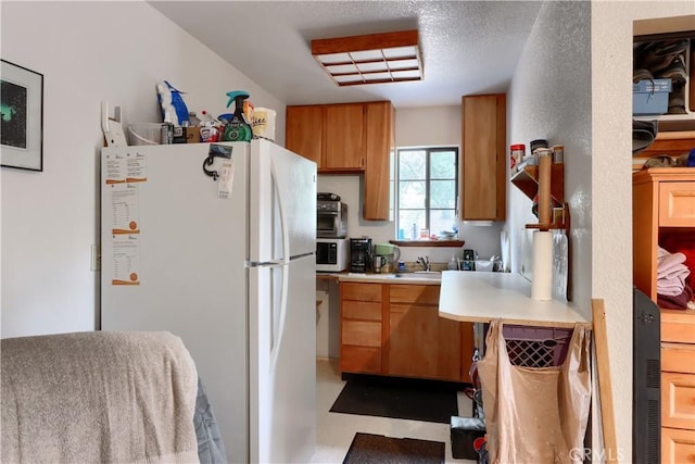 kitchen featuring a textured ceiling, sink, and white appliances