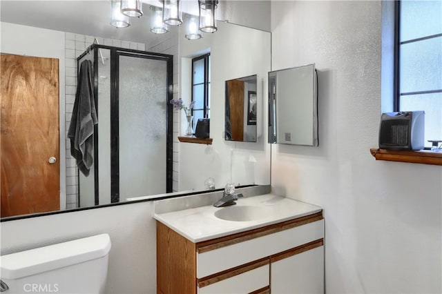 bathroom with a shower with door, vanity, and toilet