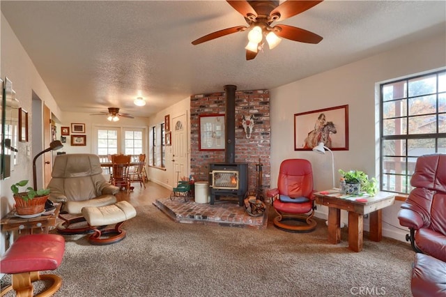 carpeted living room featuring a textured ceiling, a wood stove, and ceiling fan