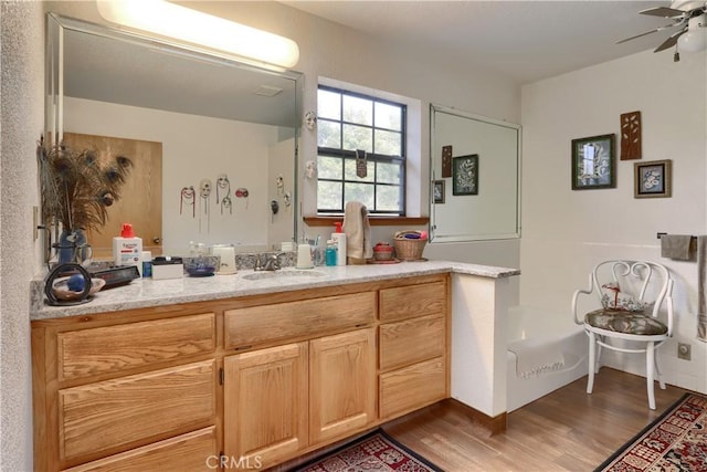 kitchen with light brown cabinets, sink, dark hardwood / wood-style floors, ceiling fan, and light stone counters