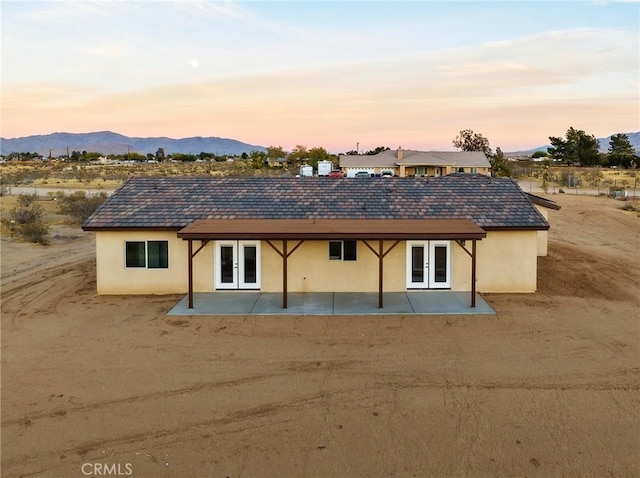 back house at dusk featuring a patio area, a mountain view, and french doors