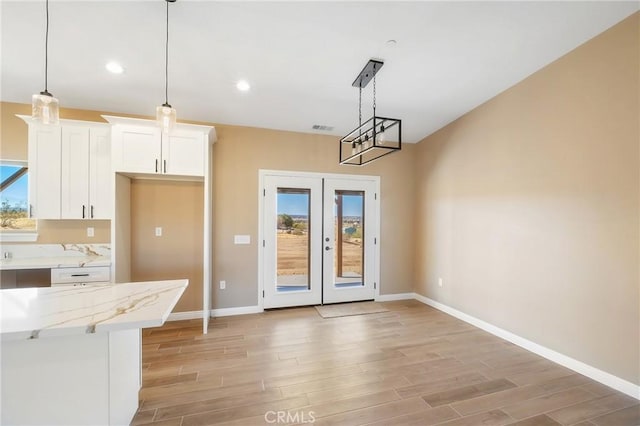 kitchen featuring white cabinets, decorative light fixtures, and a healthy amount of sunlight