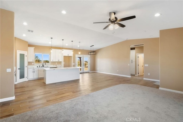 kitchen featuring white cabinets, a center island, light wood-type flooring, and pendant lighting