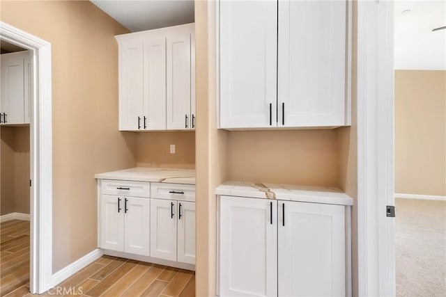 interior space featuring white cabinets, light wood-type flooring, and light stone countertops