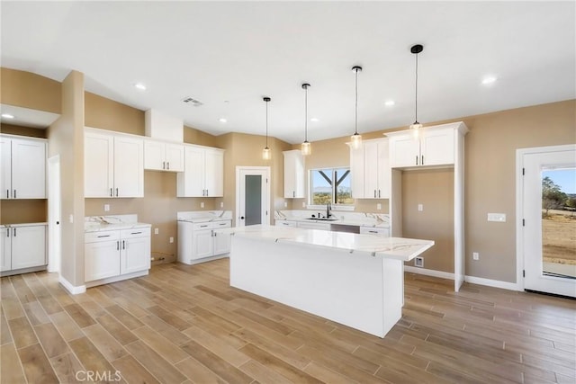 kitchen featuring a kitchen island, a healthy amount of sunlight, and white cabinetry