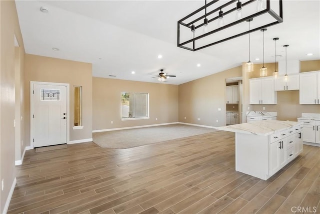 kitchen featuring light stone countertops, ceiling fan, white cabinets, hardwood / wood-style floors, and a kitchen island