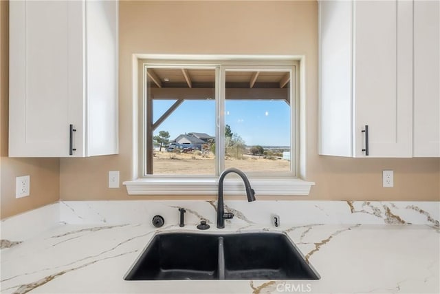 interior details with light stone countertops, white cabinetry, and sink