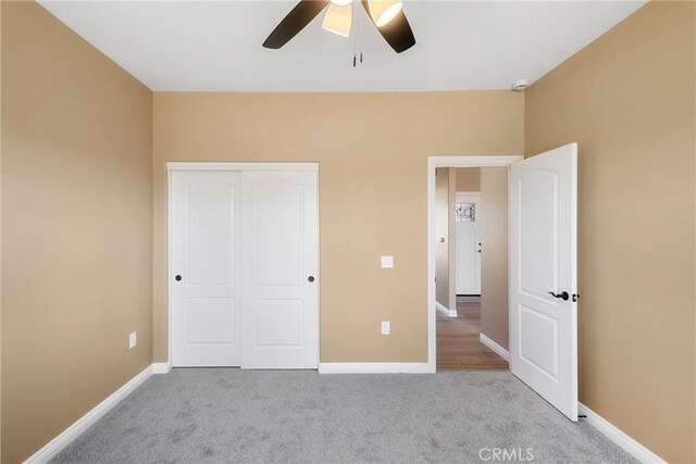 unfurnished bedroom featuring ceiling fan, a closet, and light carpet