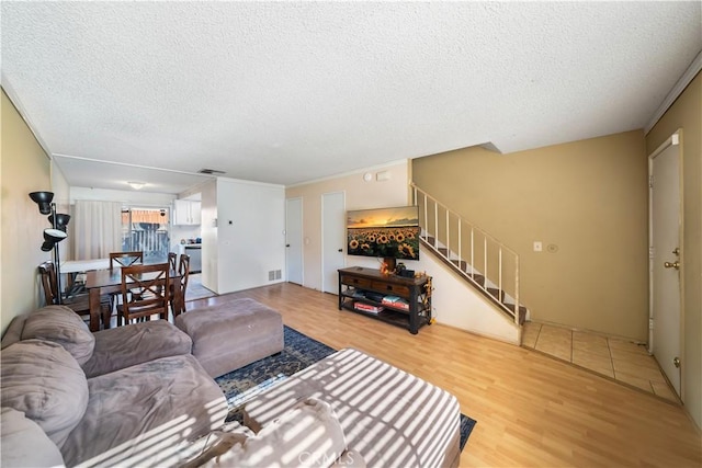 living room featuring hardwood / wood-style floors, a textured ceiling, and ornamental molding