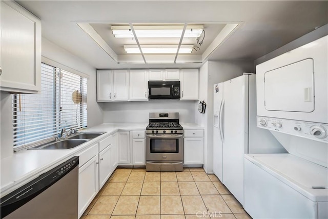 kitchen with stacked washer / drying machine, a raised ceiling, white cabinetry, and appliances with stainless steel finishes