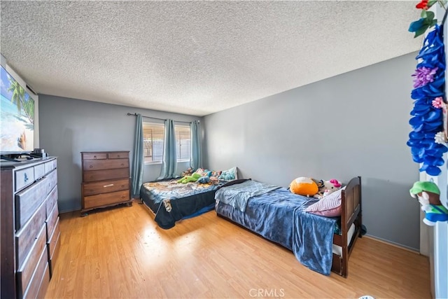 bedroom with hardwood / wood-style floors and a textured ceiling