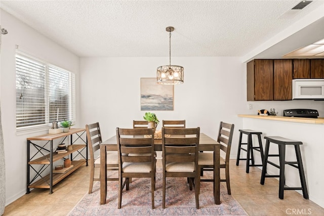 dining room with a chandelier, light tile patterned floors, and a textured ceiling