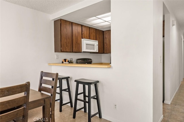 kitchen featuring a textured ceiling, kitchen peninsula, and black range oven