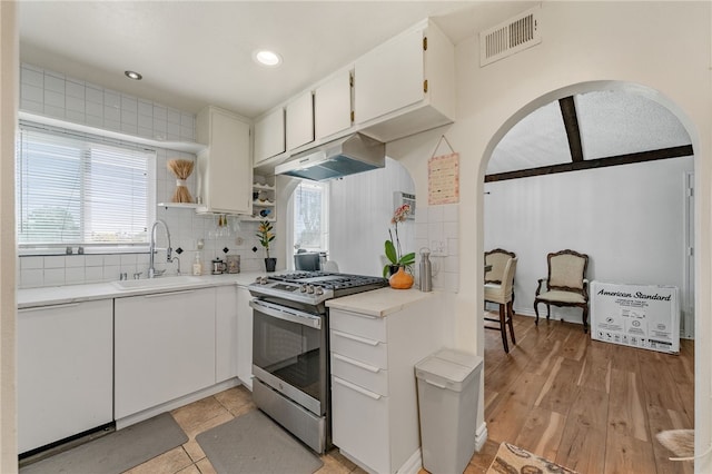 kitchen with a healthy amount of sunlight, stainless steel range with gas cooktop, sink, and white cabinets