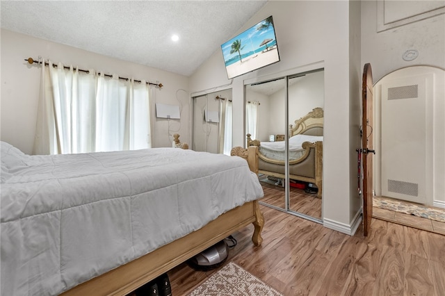 bedroom with a textured ceiling, lofted ceiling, and light wood-type flooring