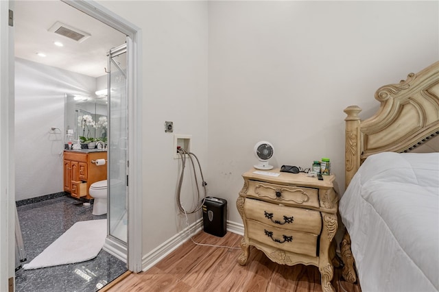 bedroom featuring hardwood / wood-style flooring and ensuite bathroom