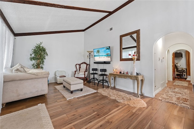 living room with hardwood / wood-style flooring, ornamental molding, vaulted ceiling, and a textured ceiling