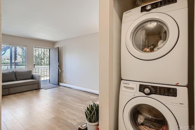 laundry area with light wood-type flooring and stacked washer and clothes dryer