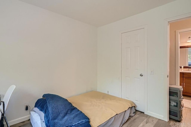 bedroom with connected bathroom, sink, and light hardwood / wood-style floors