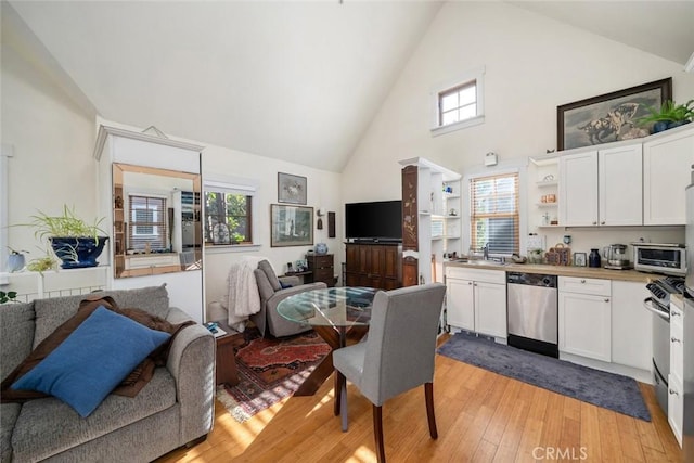 dining space with high vaulted ceiling and light wood-style floors