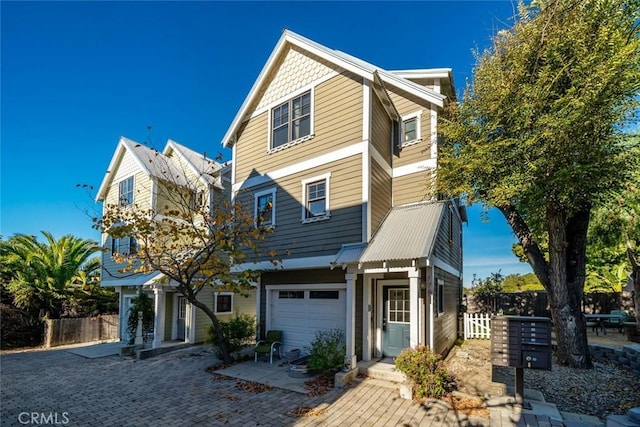 view of front of house featuring a garage, metal roof, decorative driveway, and fence