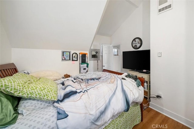 bedroom featuring lofted ceiling, baseboards, visible vents, and wood finished floors