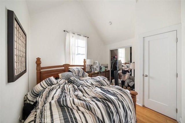 bedroom with multiple windows, light hardwood / wood-style floors, a closet, and lofted ceiling