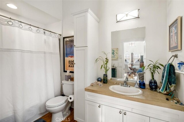 bathroom featuring a shower with curtain, hardwood / wood-style floors, vanity, and toilet