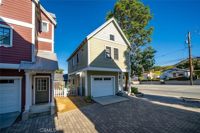 view of front of home featuring a garage, fence, and decorative driveway