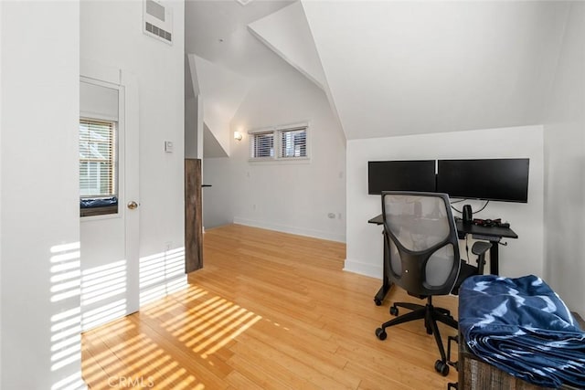 office with baseboards, visible vents, vaulted ceiling, and light wood finished floors