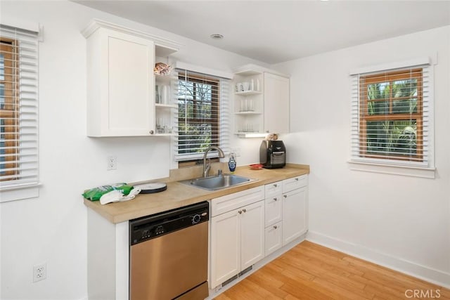 kitchen featuring light wood-style flooring, light countertops, stainless steel dishwasher, open shelves, and a sink