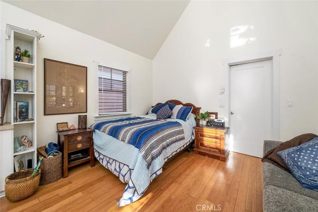 bedroom with high vaulted ceiling and light wood-type flooring