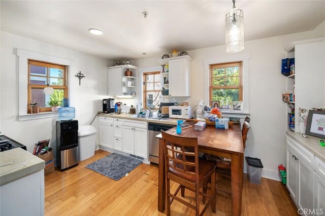 kitchen featuring plenty of natural light, stainless steel dishwasher, decorative light fixtures, light hardwood / wood-style floors, and white cabinetry