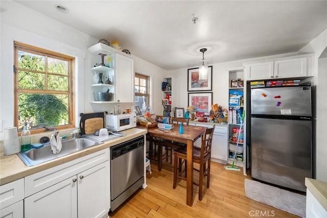 kitchen with open shelves, stainless steel appliances, light countertops, white cabinets, and a sink