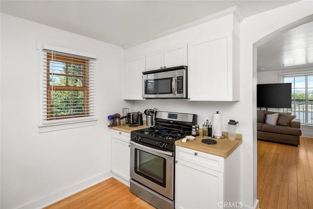 kitchen with stainless steel appliances, white cabinetry, a wealth of natural light, and light hardwood / wood-style flooring