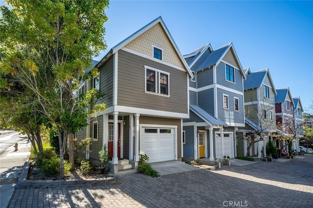 view of front of home with a garage, a residential view, and decorative driveway