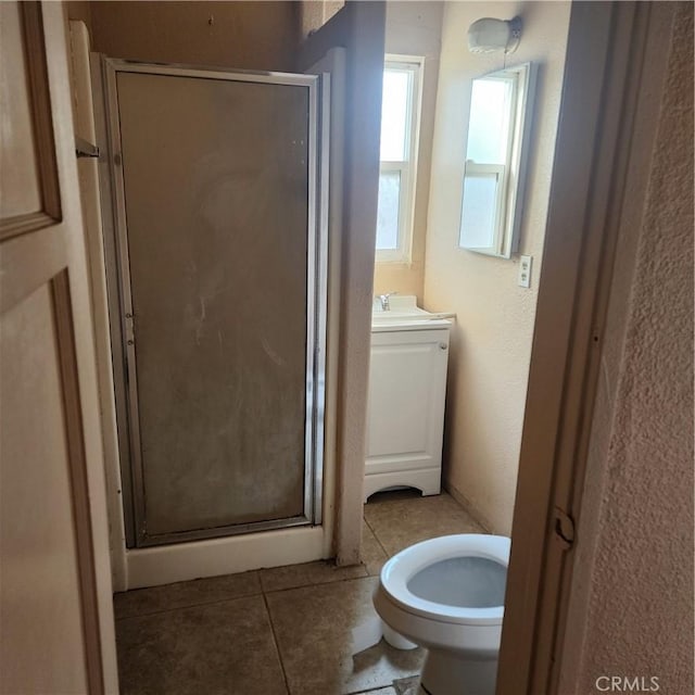 bathroom featuring tile patterned flooring, vanity, toilet, and a shower with shower door