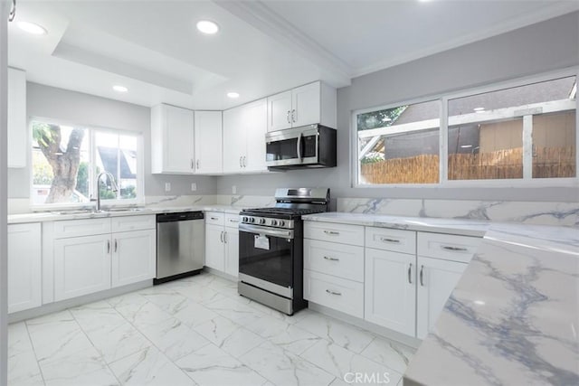 kitchen featuring a wealth of natural light, sink, white cabinets, and appliances with stainless steel finishes