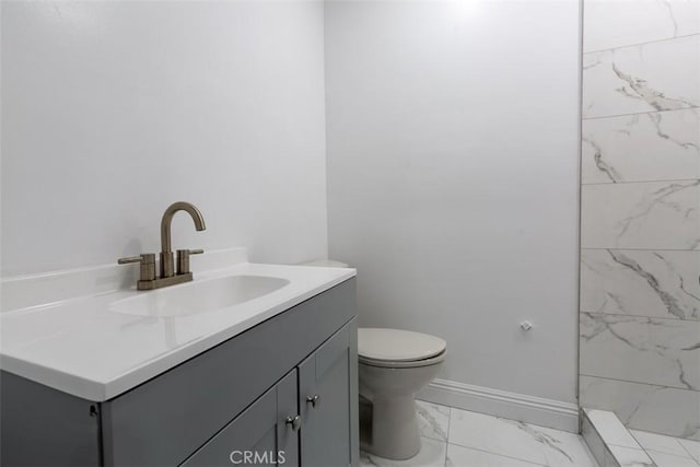 bathroom with vanity, toilet, and a tile shower