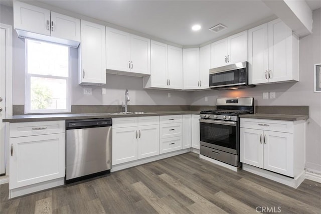 kitchen with dark wood-type flooring, white cabinets, stainless steel appliances, and sink