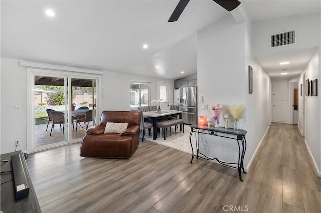 living room with light wood-type flooring, high vaulted ceiling, and ceiling fan