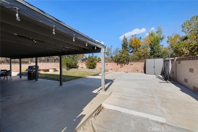 view of patio / terrace with a storage shed and a grill