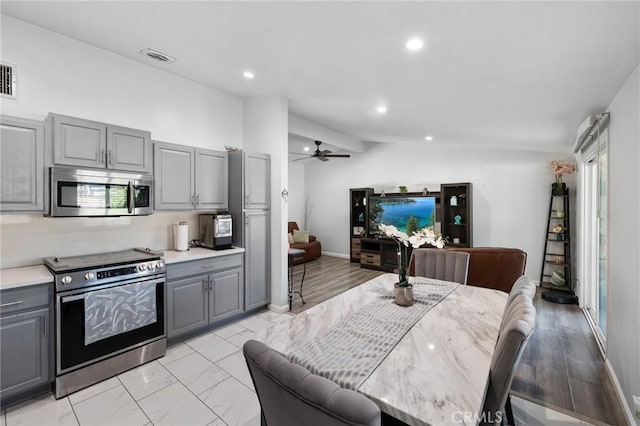 kitchen with stainless steel appliances, vaulted ceiling, ceiling fan, and gray cabinetry