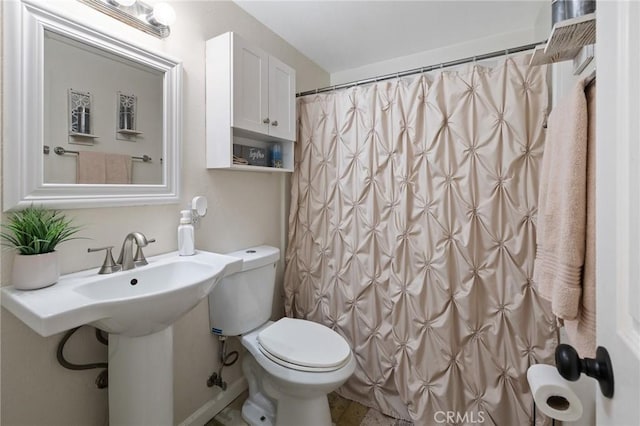 bathroom with curtained shower, toilet, and sink