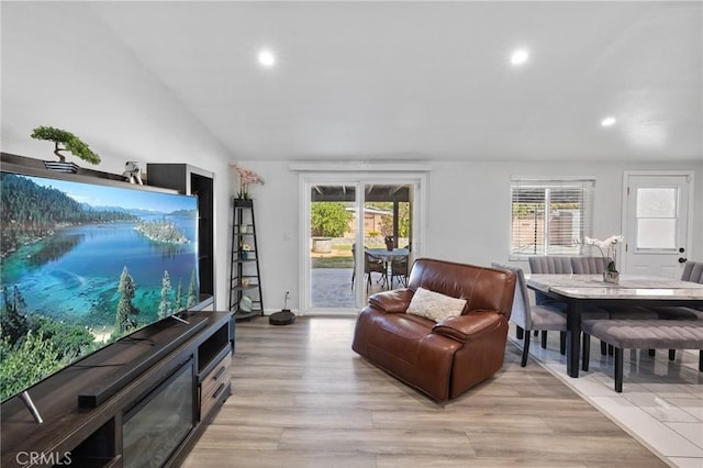 living room with plenty of natural light, light hardwood / wood-style floors, and lofted ceiling