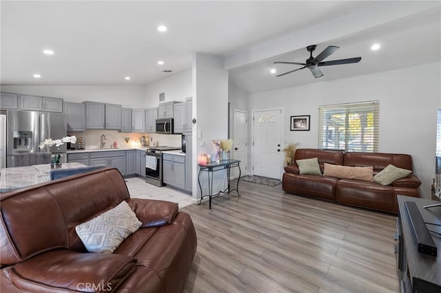 living room with lofted ceiling with beams, light hardwood / wood-style floors, ceiling fan, and sink