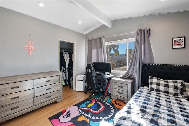 bedroom featuring lofted ceiling with beams, a closet, a walk in closet, and light hardwood / wood-style flooring