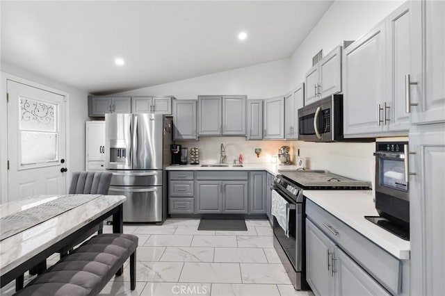 kitchen featuring stainless steel appliances, vaulted ceiling, gray cabinetry, and sink