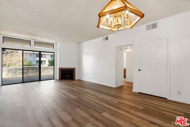 unfurnished living room with a textured ceiling, a notable chandelier, and hardwood / wood-style flooring